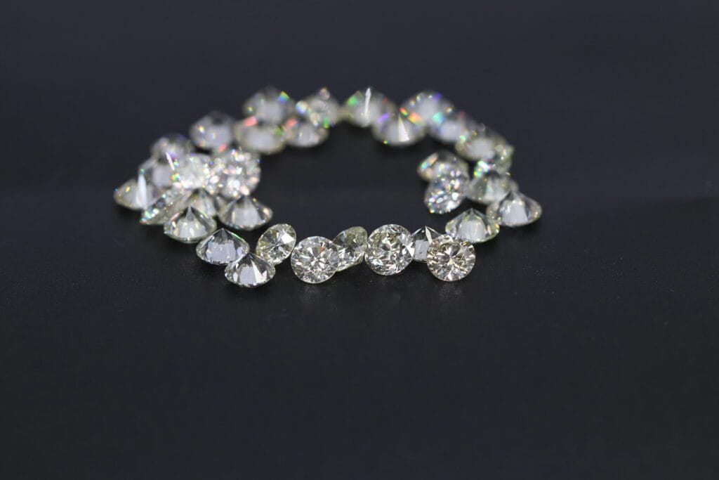 Collection of sparkling round-cut loose diamonds arranged on a black surface, highlighting their clarity and brilliance.